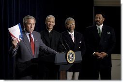 Holding up a book about his Faith-Based Initiatives, President George W. Bush talks with urban leaders in the Eisenhower Executive Office Building Wednesday, July 16, 2003. Standing behind the President are, from left, Rev. Bishop John Huston Ricard of Fla., Rev. Eugene F. Rivers III of Mass., and Tony Evans of Texas. White House photo by Eric Draper.